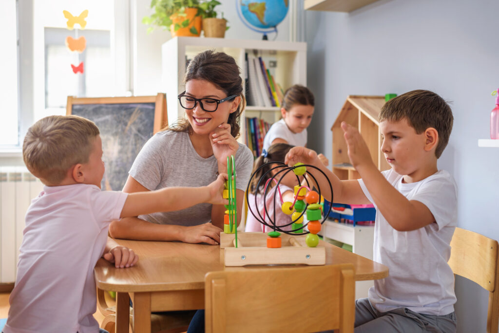 preschool teacher with children playing with colorful wooden didactic toys at kindergarten